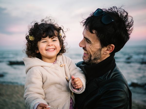 father holding little daughter at the beach