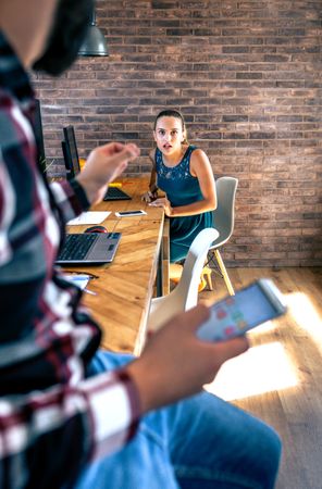 Woman surprised by what her coworker is telling