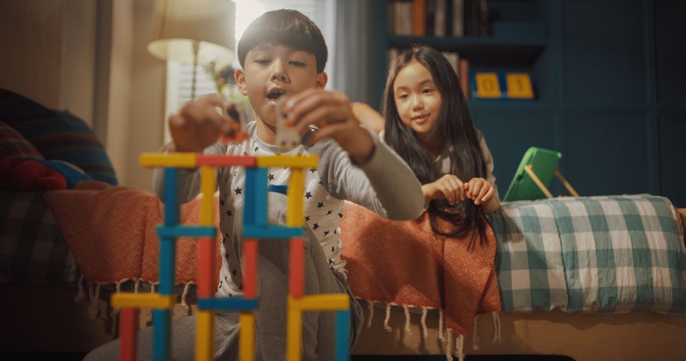 Portrait of Focused Little Boy Playing with Construction Building Blocks, His Smart Little Sister Using Digital Tablet Computer while in Children's Room.