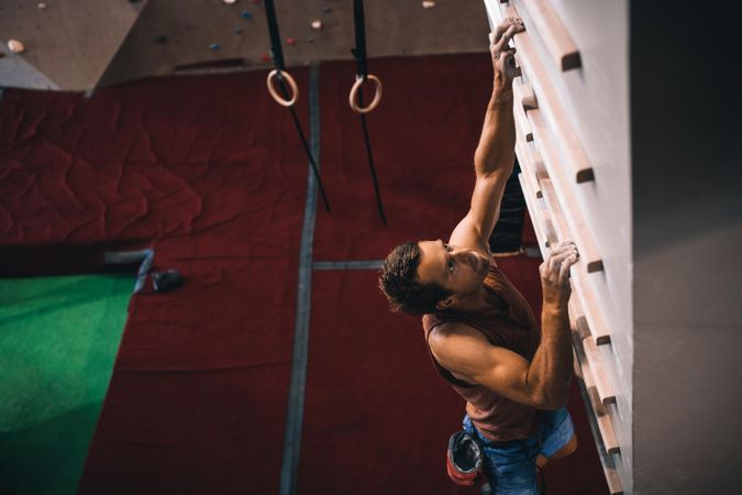 Skilled rock climber practicing wall climbing on campus board