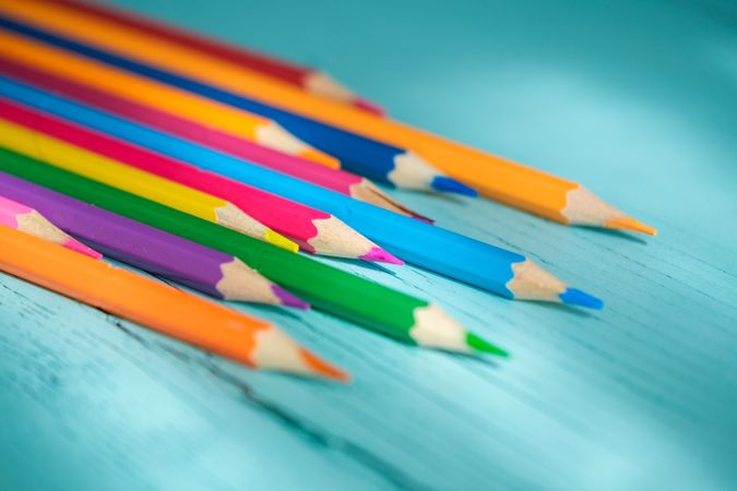 Coloured pencils arranged in a circle on a wooden background