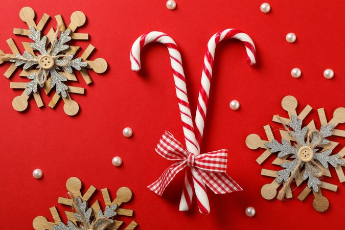 Candy canes and decorative snowflakes on red background, top view