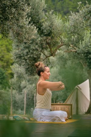 Woman practicing stress relief in green forest with music