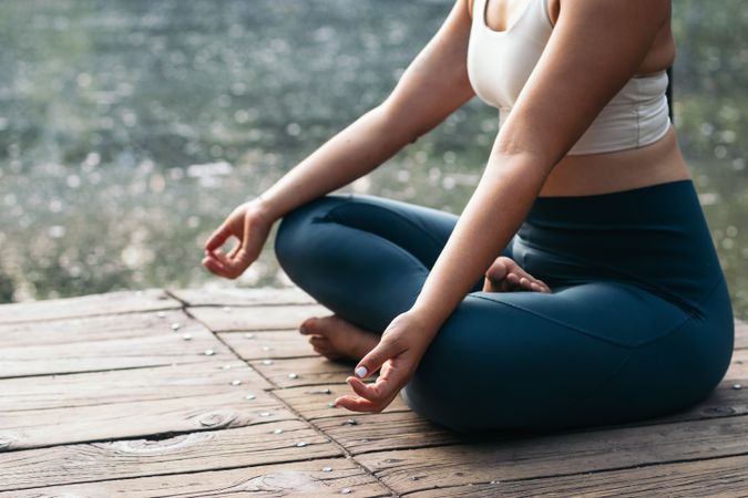 Woman meditating in nature near a lake