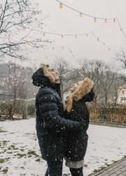 Smiling couple having fun on street near tree with fairy lights