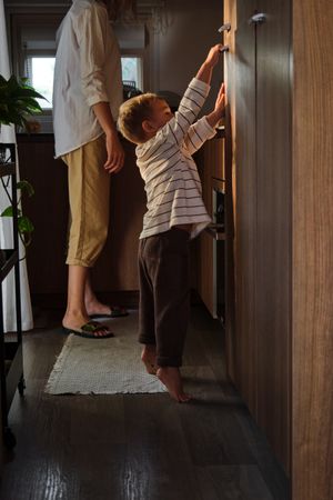Son reaching out door handle near crop mother
