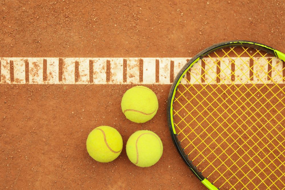 Tennis racquet with tennis balls on clay court