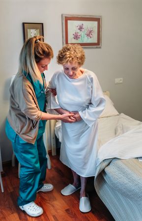 Caregiver helping older patient to stand up