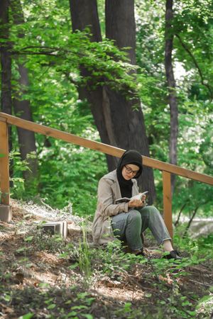 Woman in headscarf and glasses reading a book