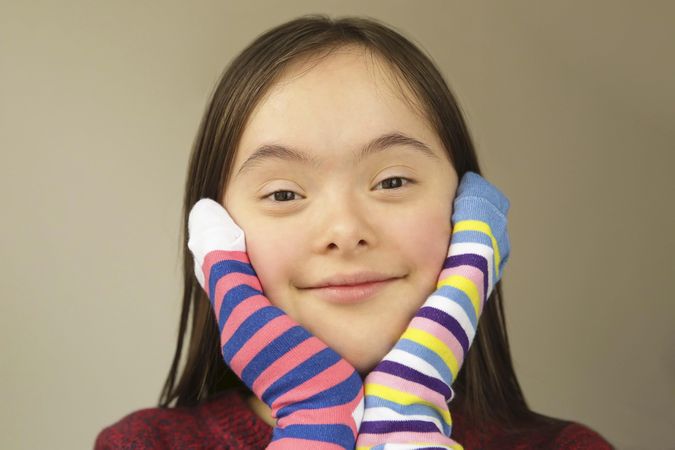Young girl with Down syndrome playing with socks on her hands