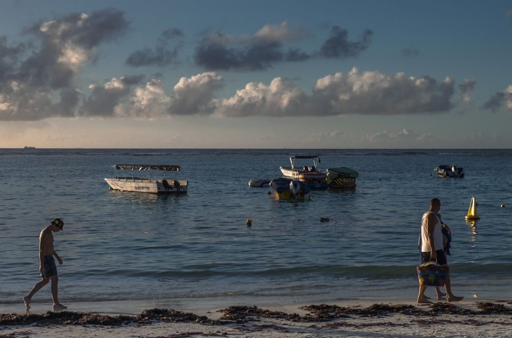 People walking along waterfront with small boats