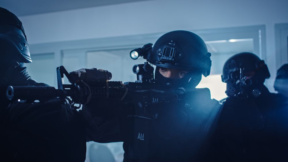 Close Up Portraits of Masked Squad of Armed SWAT Police Officers Storm a Dark Seized Office Building with Desks and Computers.