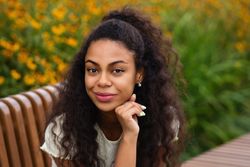Portrait of Black female smiing on bench in front of flowers
