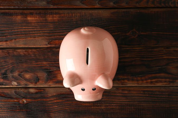 Happy piggy bank on wooden background, space for text and top view. Finance, saving money