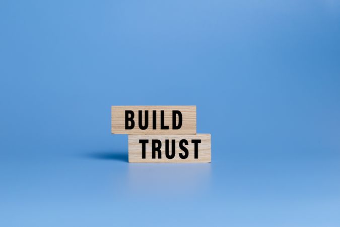 male hand putting wooden blocks with build trust words isolated on blue background