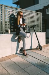 Businesswoman using mobile with her scooter next