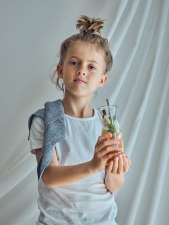 Serious boy holding glass bottle and looking at camera