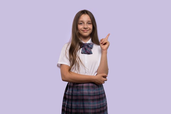 Girl in school uniform raising one finger