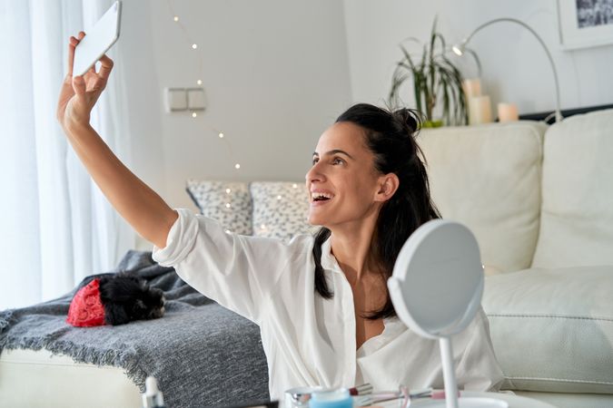 Woman taking selfie on smartphone while sitting on floor