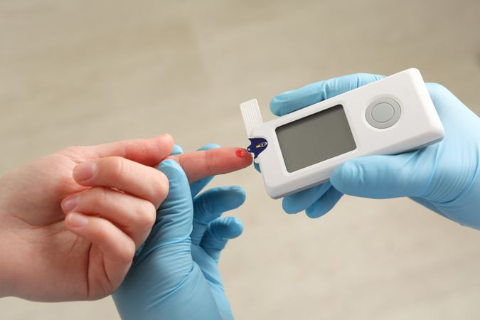 Doctor checking blood sugar level of woman, close up