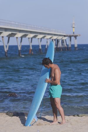 Male surfer standing with his board near the coast