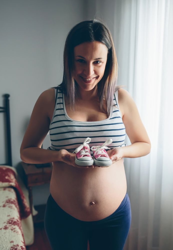 Pregnant showing baby sneakers