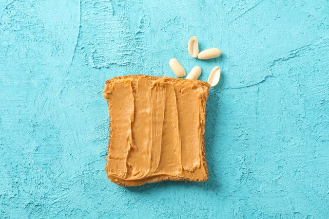 Peanut butter sandwich and peanut on color background, space for text and top view