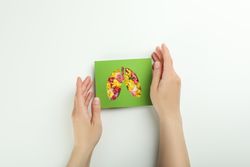 Hands holding lung shape cut out of green paper with yellow flowers underneath, pollen concept