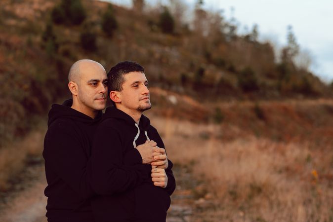 Men hugging on road on hill
