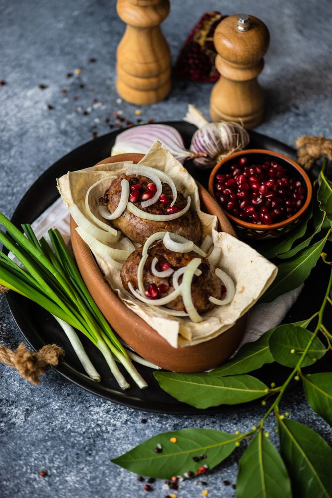 Georgian meal of abkhazura meat cutlets on plate with pomegranate seeds and bay leaves