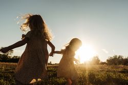 Carefree sisters playing in countryside against sunset
