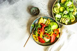 Top view of two healthy vegetable salad with arugula and avocado with copy space