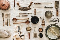 Vintage kitchen utensils and knifes artfully arranged on light tablecloth