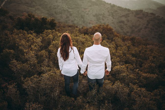Peaceful couple holding hands while standing at hilly valley