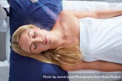 Peaceful woman lying back in towel receiving treatment on shoulder 5kRvyo