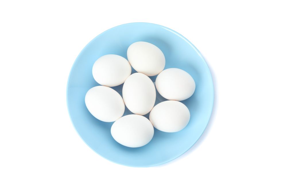 chicken eggs in plate isolated on plain background, top view