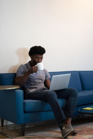 Man with prosthetic leg sitting with coffee and laptop