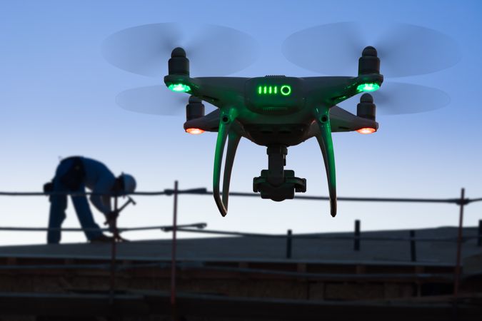 Silhouette of Unmanned Aircraft System Quadcopter Drone In The Air at Construction Site