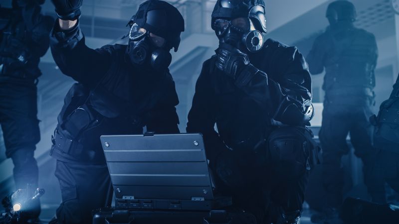 Masked Team of Armed SWAT Police Officers with Rifles are in Dark Seized Office Building with Desks and Computers.