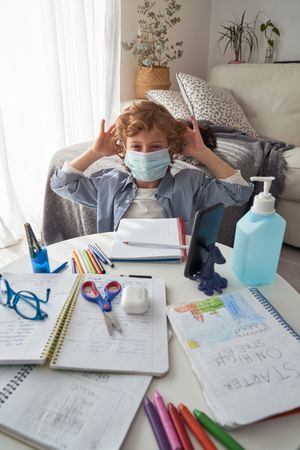 Little child wearing mask while studying at home
