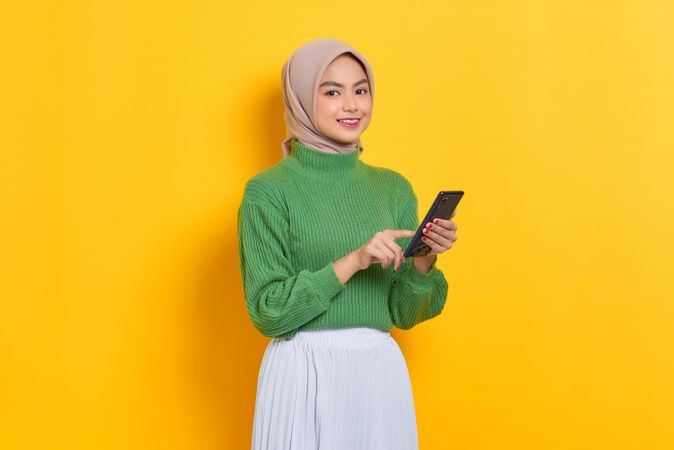 Happy woman in headscarf looking up from her smartphone