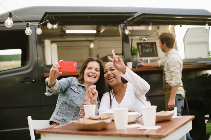 Adult women taking selfie near food truck