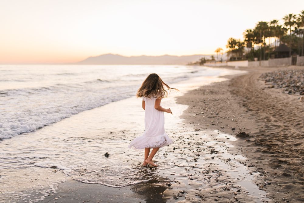 Excited girl running along beach in daylight