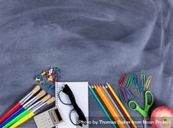 Back to school basic supplies placed on bottom part of erased chalkboard 0KY3N4