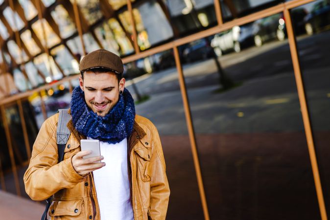 Stylish guy using smartphone outside modern building
