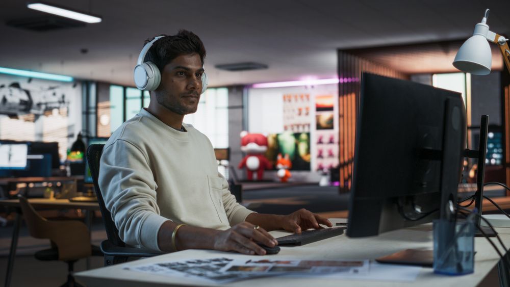 Portrait of a Stylish Indian Man Working on Desktop Computer in a Company Office.