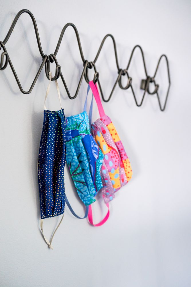 Three colorful masks hang on a coat rack