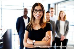 Smiling woman in glasses pictured in front of her colleagues in a bright office 4Ol7jb