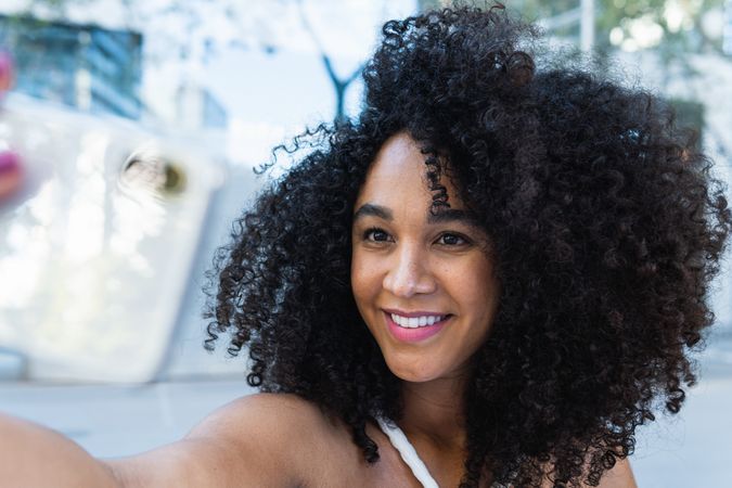 Happy Black woman with curly hair reaching hand to camera