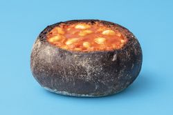 Baked beans in bread crust, close-up, on a blue table